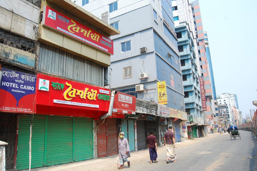 Pedestrians walk past closed shops and restaurants during a shutdown enforced by the government as a preventive measure against the coronavirus outbreak at Topkhana Road in Purana Paltan, Dhaka — Focus Bangla/Files