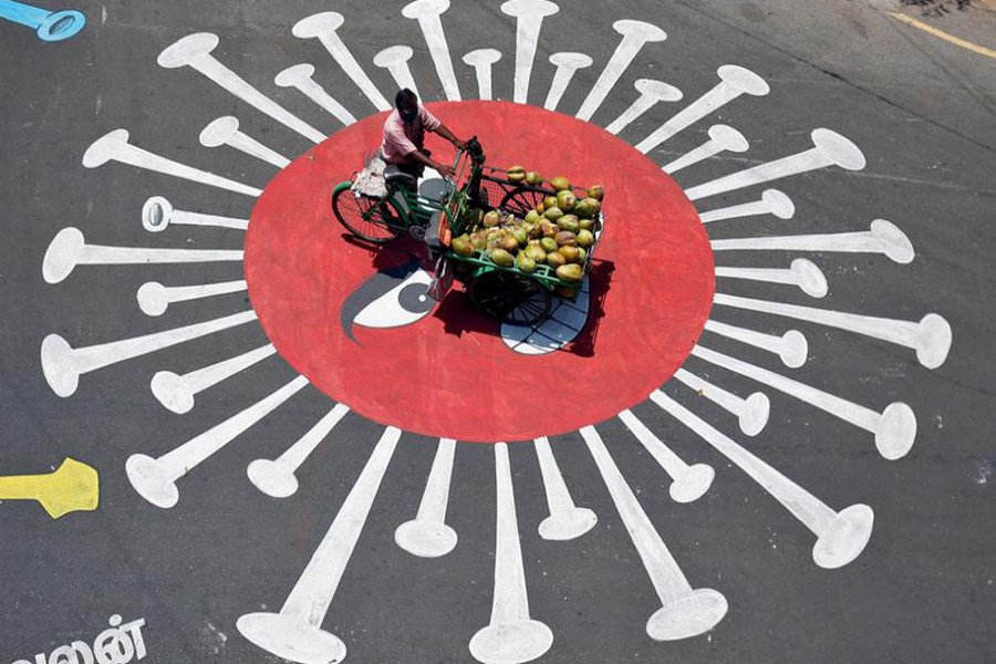 A man selling coconuts rides his trishaw on a graffiti on a road depicting the coronavirus as an attempt to raise awareness about the importance of staying at home during the nationwide lockdown to slow the spreading of the coronavirus disease (COVID-19), in Chennai, India on April 13, 2020 — Reuters/Files