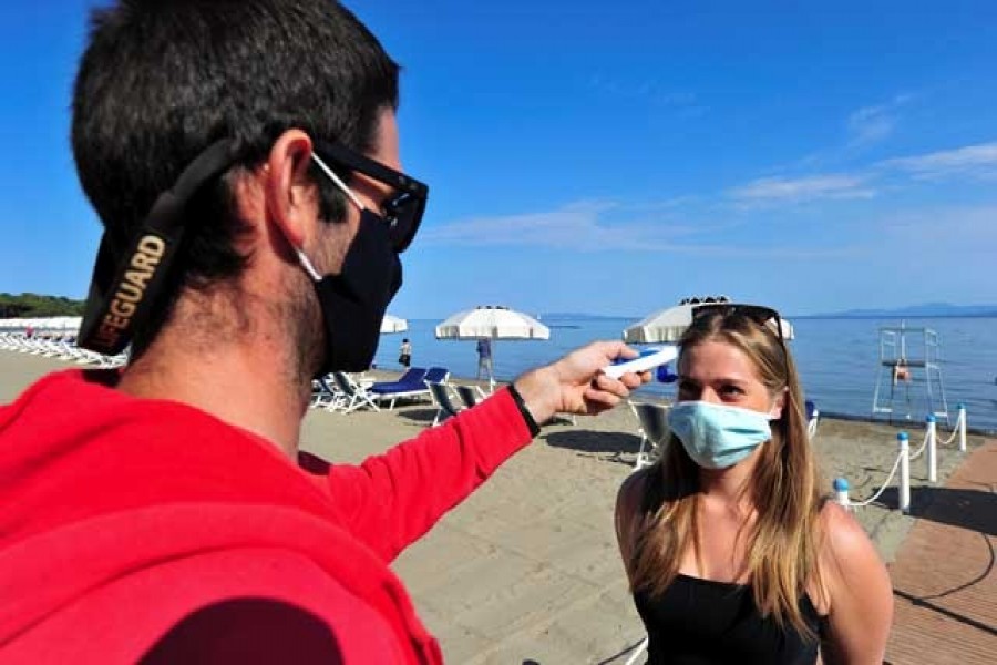 A lifeguard wearing a protective face mask takes the temperature of a woman at a newly reopened beach after months of closure due to an outbreak of the coronavirus disease (COVID-19), at Punta Hidalgo, in Punta Ala, Italy, May 31, 2020. — Reuters