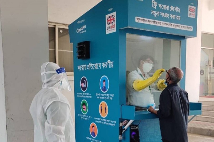 A healthcare worker takes a swab sample from a man at the one-stop digital booth for COVID-19 screening and testing – first of its kind in Bangladesh, at Mugda Medical College Hospital in Dhaka — Collected