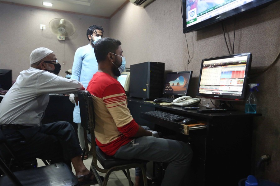 Traders, wearing protective gears, monitoring stock price movements on computer screens at a brokerage house in the capital city — FE/Files