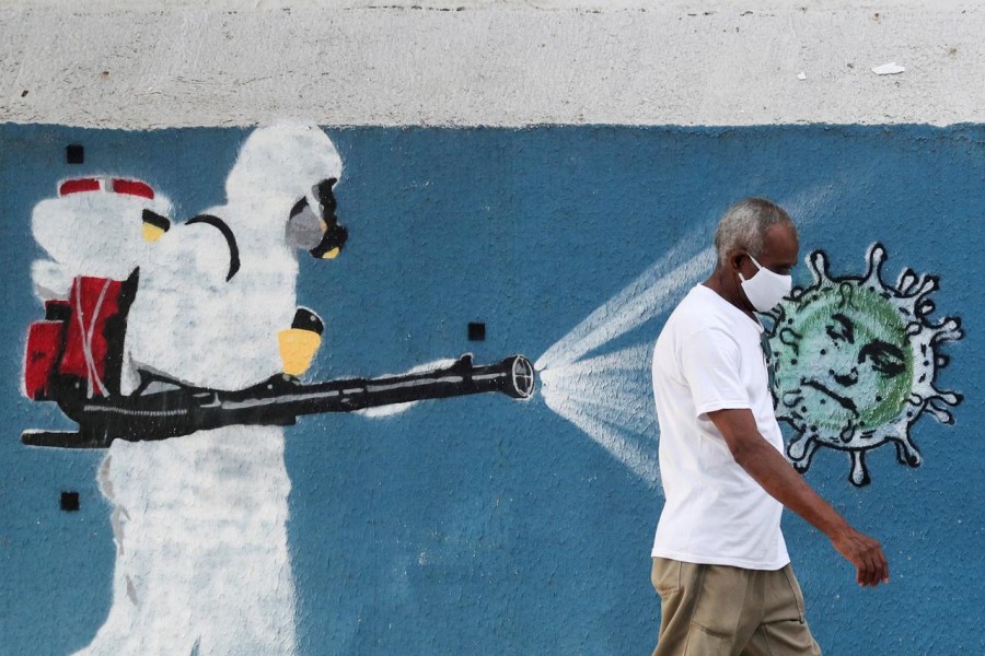 A man walks next to a graffiti depciting a cleaner wearing protective gear spraying viruses with the face of Brazil's President Jair Bolsonaro amid the coronavirus disease (Covid-19) outbreak, in Rio de Janeiro, Brazil on June 12, 2020 — Reuters/Files