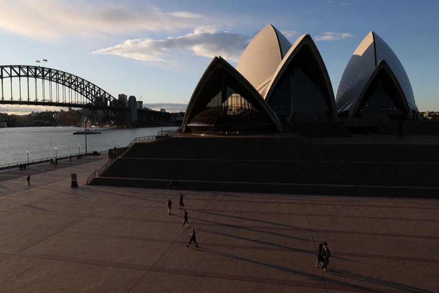 People are seen walking in front of the Sydney Opera House and Sydney Harbour Bridge following the easing of restrictions implemented to curb the spread of the coronavirus disease (COVID-19) in Sydney, Australia, June 23, 2020. REUTERS/Loren Elliott/File photo   