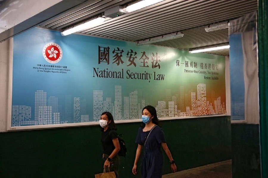 Women walk past a government-sponsored advertisement promoting the new national security law as a meeting on national security legislation takes place in Hong Kong, China, June 29, 2020 — Reuters