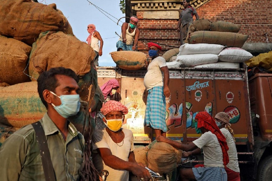 Labourers wearing protective face masks load grocery items onto a supply truck at a wholesale market during the coronavirus disease (Covid-19) outbreak in Kolkata, July 24, 2020 — Reuters