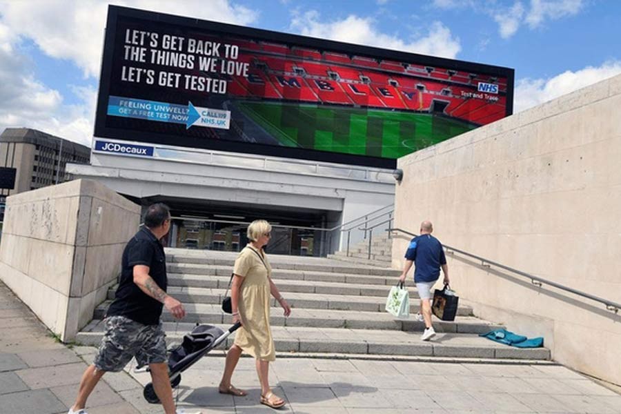 People walking past a British government public health campaign advertisement encouraging people to get tested, amid the spread of the coronavirus disease (COVID-19), in London on Sunday –Reuters Photo