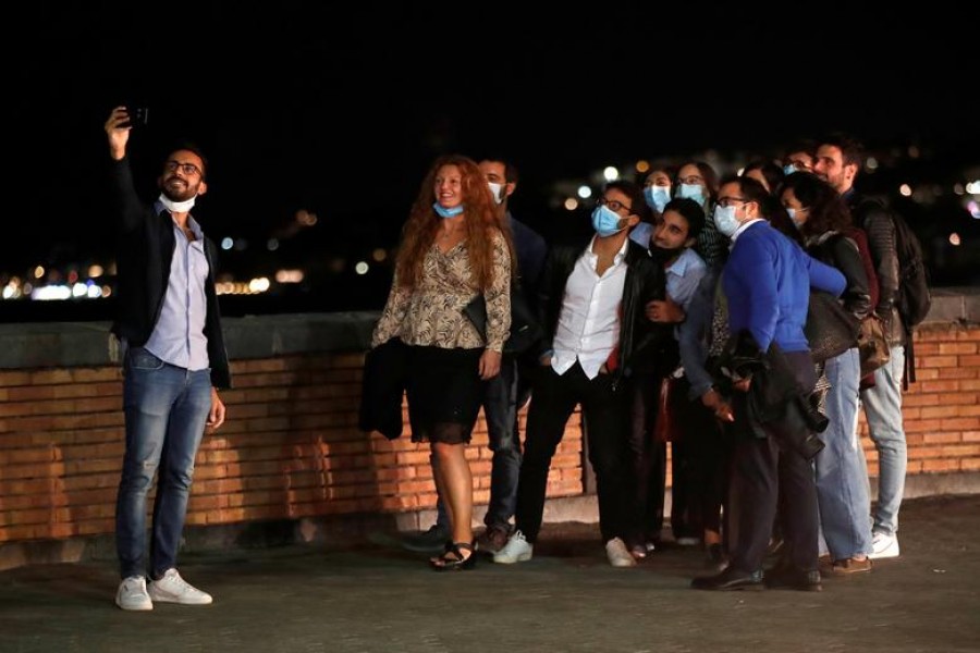 People pose for a selfie in Naples, where masks are required outdoors 24 hours a day and bars and restaurants are required to close at 11.00.p.m. (2100GMT), as part of efforts to contain the coronavirus disease (COVID-19) outbreak, Italy October 6, 2020. REUTERS/Ciro De Luca