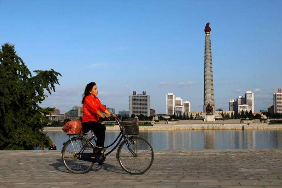 A woman riding a bicycle as Juche Tower is seen in the background along the Taedong river in Pyongyang, North Korea, last month –Reuters photo