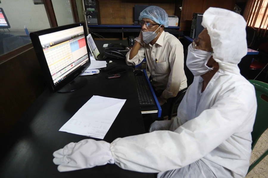 Traders, in protective suits, monitoring stock price movements on computer screens at a brokerage house in the capital city — FE/Files