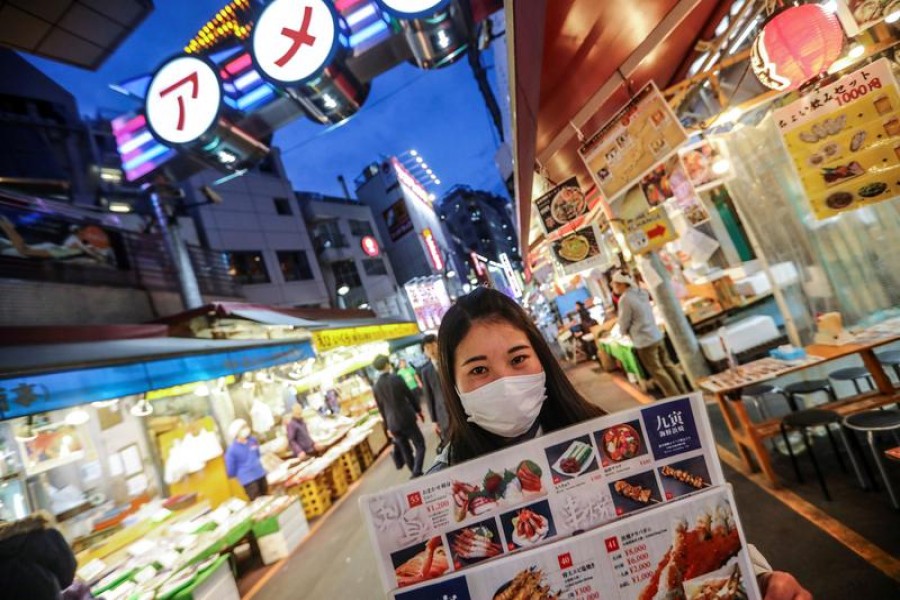 A woman wooing visitors for her restaurant at the Ameya Yokocho market wears a protective face mask following an outbreak of the coronavirus disease (COVID-19) in Tokyo, Japan March 13, 2020. REUTERS/Hannibal Hanschke/File Photo