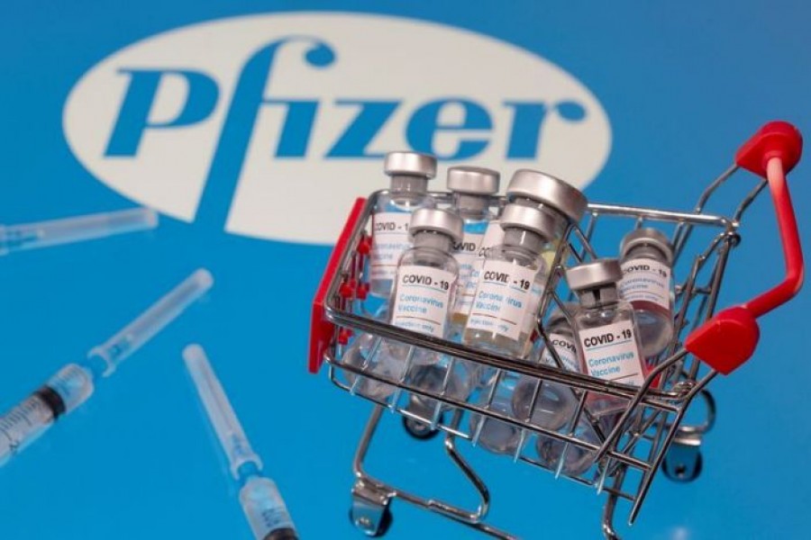 A small shopping basket filled with vials labeled ''COVID-19 - Coronavirus Vaccine'' and medical sryinges are placed on a Pfizer logo in this illustration taken on November 29, 2020 — Reuters/Files