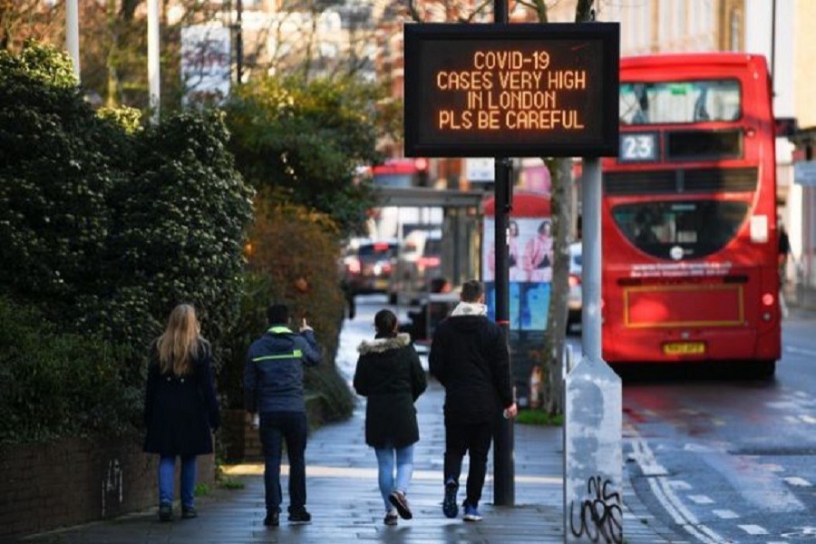 A person gestures towards a sign with a public health information message, amid the spread of the coronavirus disease (Covid-19), as new restrictions come into force, in London, Britain, December 20, 2020 — Reuters