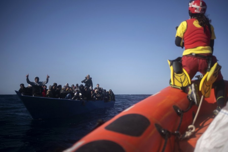 Migrants from Eritrea, Egypt, Syria and Sudan, are assisted by aid workers of the Spanish NGO Open Arms, after fleeing Libya on board a precarious wooden boat in the Mediterranean sea, about 110 miles north of Libya, on Saturday, Jan. 2, 2021. (AP Photo/Joan Mateu)