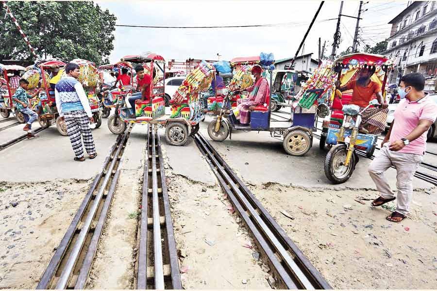 Battery-run tricycles known as easybikes wait for passengers on the level-crossing on the Hajee Camp Road near the Airport Railway Station in the city on Sunday, defying the risk that an accident can happen any time — FE file photo by KAZ Sumon