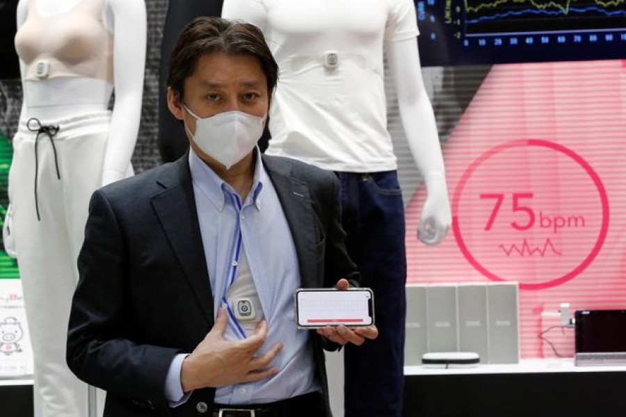 Toyobo's staff shows the 'COCOMI' clothing, which can acquire physiological information data, and a smartphone displaying the measured heart rate during its demonstration at the Wearable Expo in Tokyo, Japan, January 20, 2021. REUTERS/Kim Kyung-Hoon