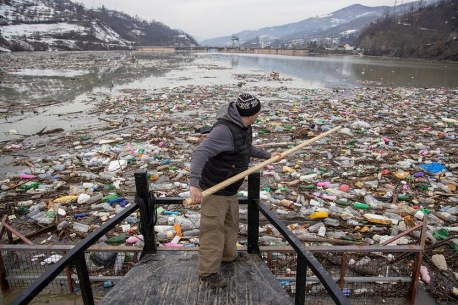 A worker collects plastic trash that litters the polluted Potpecko Lake near a dam's hydroelectric plant near the town of Priboj, Serbia on January 29, 2021 — Reuters photo