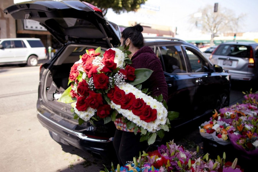 A woman lifts a funeral display into a car in the flower district as the coronavirus disease (Covid-19) outbreak continues, ahead of Valentine's Day in Los Angeles, California, US, February 4, 2021. REUTERS/Lucy Nicholson