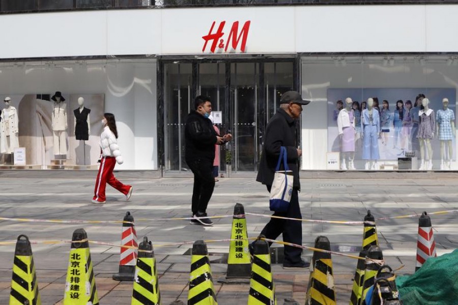 FILE PHOTO: People walk past a store of the Swedish fashion retailer H&M at a shopping complex in Beijing, China, March 25, 2021. REUTERS/Florence Lo