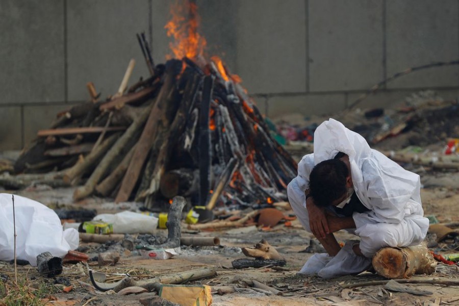 A man mourns as he sits next to the burning pyre of a relative, who died from the coronavirus disease (Covid-19), during his cremation, at a crematorium in New Delhi, India on May 5, 2021 — Reuters photo