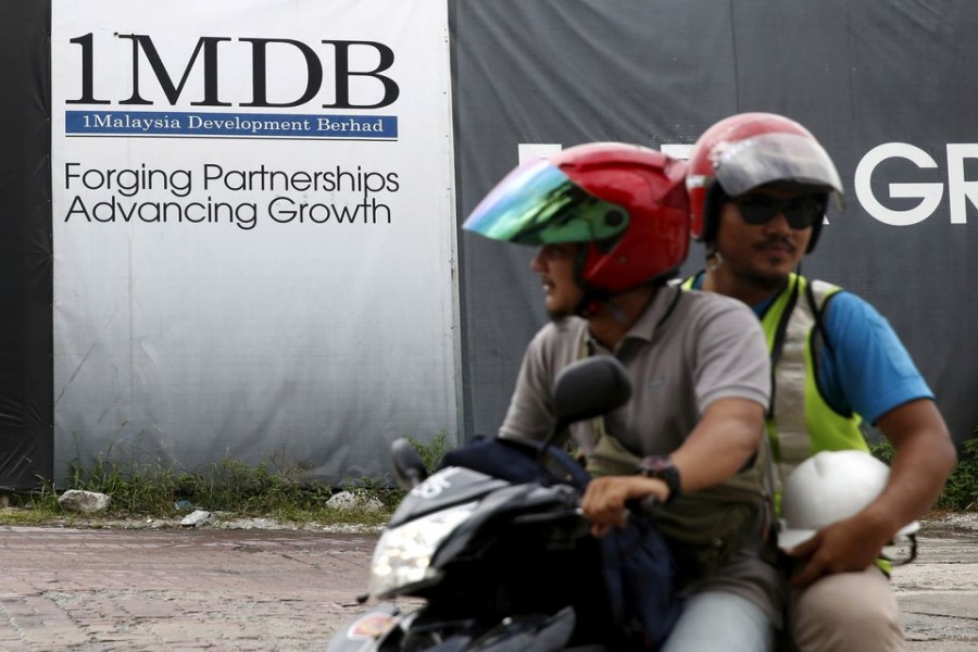 Motorcyclists pass a 1Malaysia Development Berhad (1MDB) billboard at the Tun Razak Exchange development in Kuala Lumpur, Malaysia, February 3, 2016. REUTERS/Olivia Harris