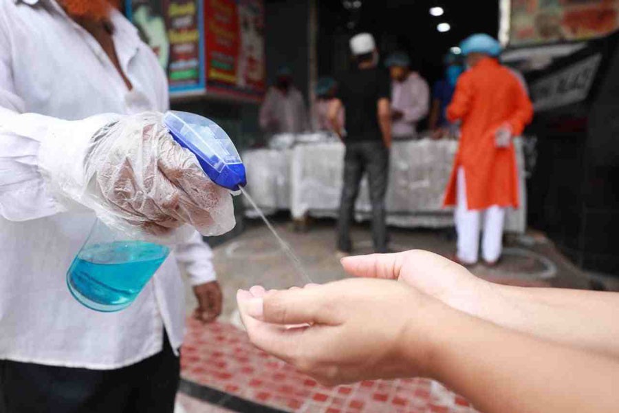 A staff gives hand sanitizer to a customer before entering a shop in Dhaka. 	—UNB Photo