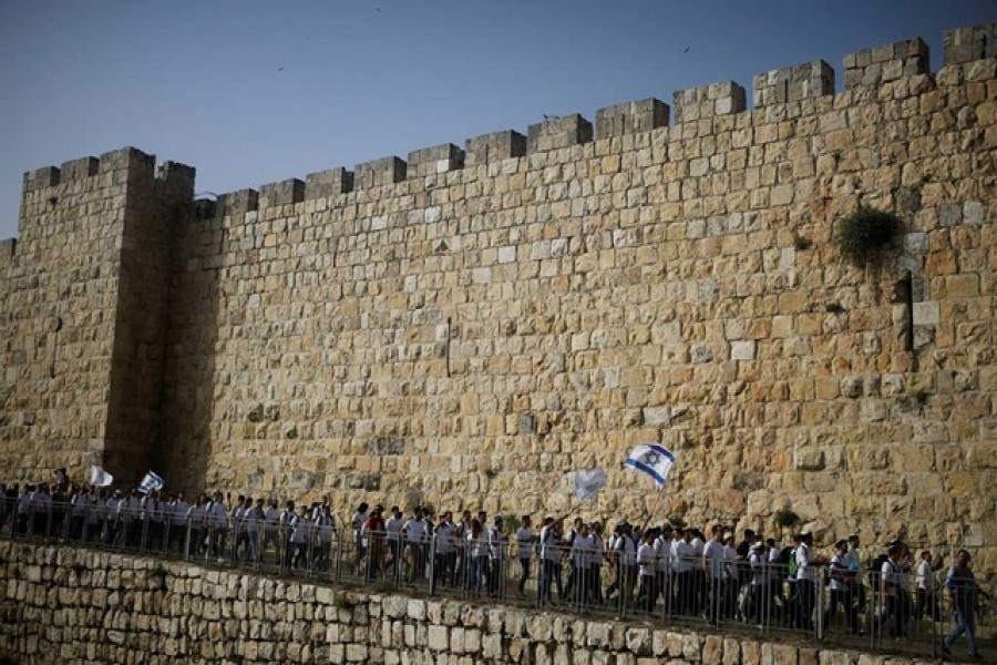 Youths wave Israeli flags during a parade marking Jerusalem Day amid Israeli-Palestinian tension as they march along the walls surrounding Jerusalem's Old City, May 10, 2021. REUTERS