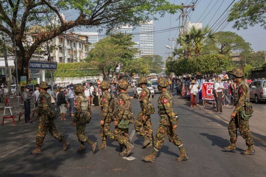 Soldiers cross a street as people gather to protest against the military coup, in Yangon, Myanmar, February 15, 2021— Reuters