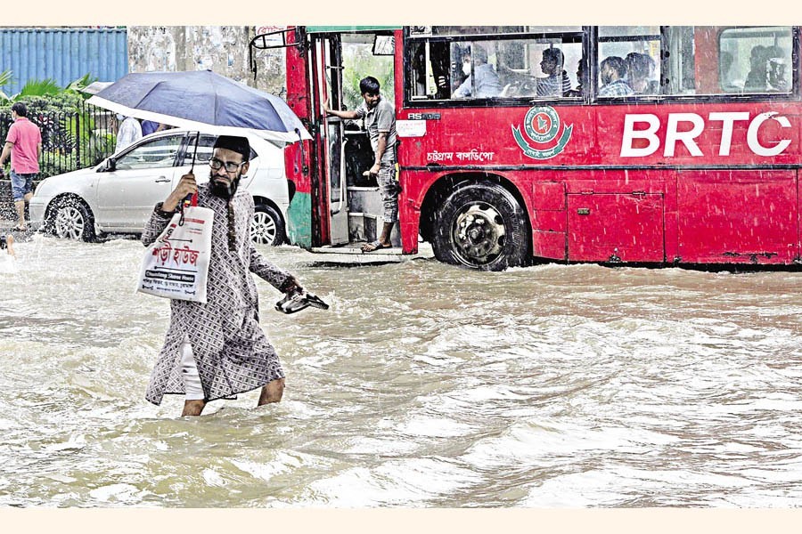 A man wades through knee-deep water in Solosharar No. 2 Gate area in Chattogram city on Wednesday as heavy overnight rain led to waterlogging in many parts of the city — Focus Bangla