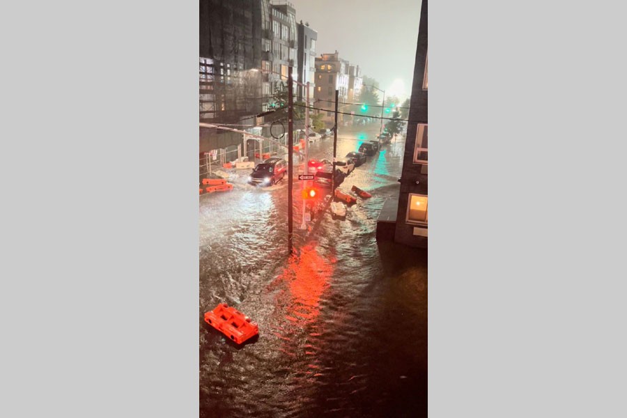 A vehicle moves along a flooded road as safety barriers float in floodwaters in Williamsburg, in the Brooklyn borough of New York City, New York, US September 1, 2021, in this still image taken from video obtained from social media. Mandatory credit JAYMEE SIRE/via REUTERS