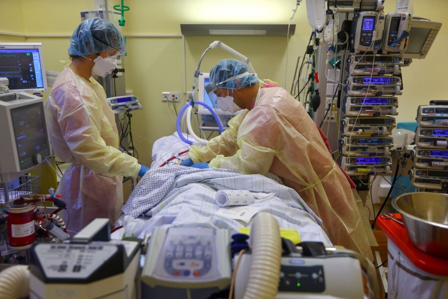 Members of the medical staff in protective suits treat a patient, on extracorporeal membrane oxygenation (ECMO) treatment, suffering from the coronavirus disease (COVID-19) in the Intensive Care Unit (ICU) at Havelhoehe Community Hospital in Berlin, Germany, December 6, 2021. REUTERS/Fabrizio Bensch