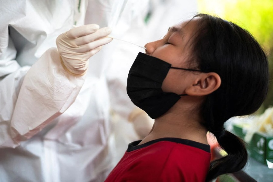 A health worker from Zendai organisation in personal protective equipment (PPE) takes a swab sample from a girl for a rapid antigen test amid the coronavirus disease (COVID-19) outbreak, in Bangkok, Thailand, January 5, 2022. REUTERS/Athit Perawongmetha