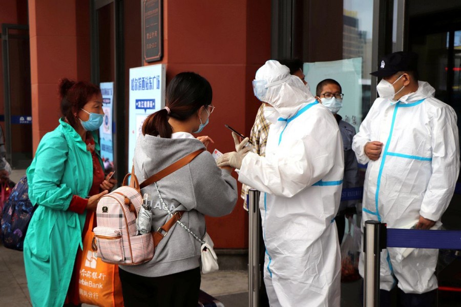 Staff members in protective suits check proof of negative test results for travellers at an entrance to the Harbin West Railway Station following new local cases of the coronavirus disease (COVID-19) in Harbin, Heilongjiang province, China September 22, 2021. cnsphoto via REUTERS
