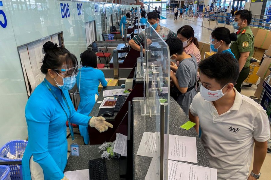 Passengers wearing protective face masks check-in at Noi Bai International Airport, as the Vietnamese government has allowed reopening several domestic air routes amid the coronavirus disease (COVID-19) pandemic, in Hanoi, Vietnam, October 10, 2021. Picture taken October 10, 2021. REUTERS/Nguyen Thinh Tien