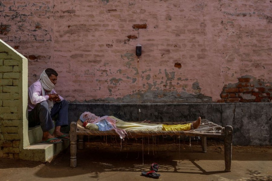 A man sits next to his wife, who was suffering from a high fever, as she intravenously receives rehydration fluid at a makeshift clinic during a surge of the coronavirus disease in Parsaul village located in the northern state of Uttar Pradesh, India, May 22, 2021. REUTERS/Adnan Abidi. Pulitzer Prize Winner for Feature Photography