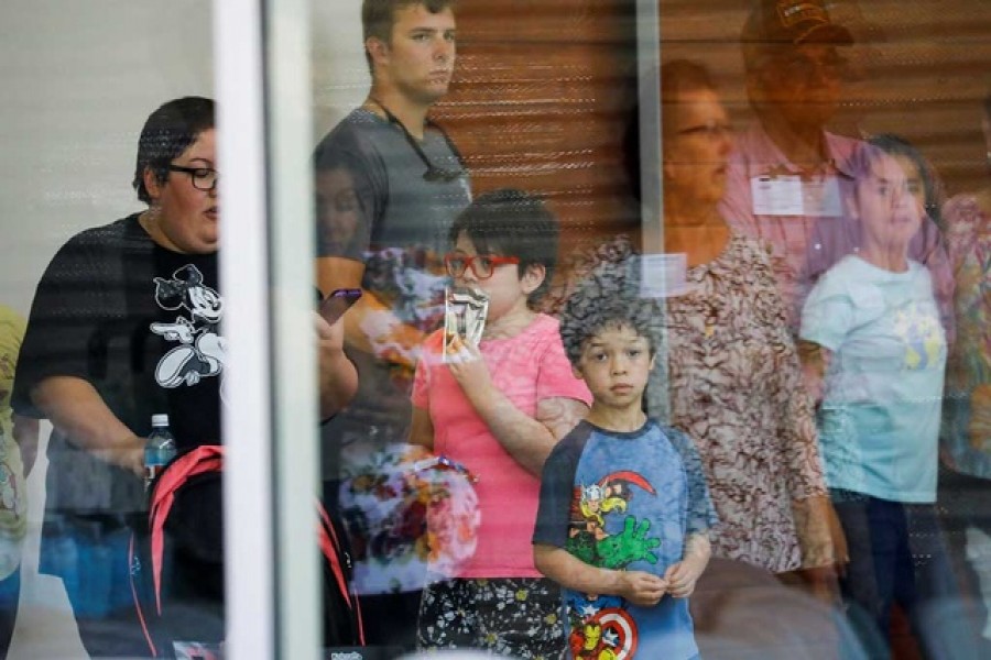 A child looks on through a glass window from inside the Ssgt Willie de Leon Civic Center, where students had been transported from Robb Elementary School after a shooting, in Uvalde, Texas, US, May 24, 2022. Reuters