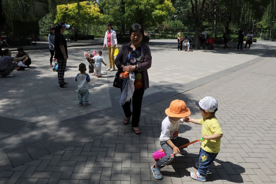 Children play next to adults at a park in Beijing, China June 1, 2021. REUTERS/Tingshu Wang