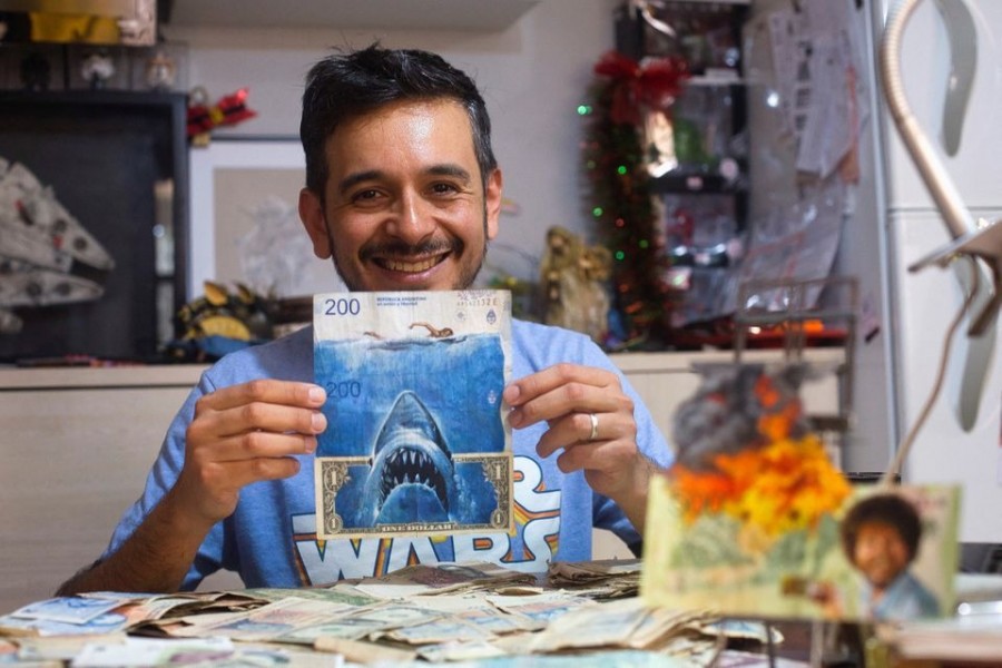 Artist Sergio Diaz holds intervened Argentine pesos bills and a US dollar depicting Steven Spielberg's movie "Shark" as a parody of Argentina's ever-increasing inflation, in Salta, Argentina on December 30, 2022 — Reuters photo