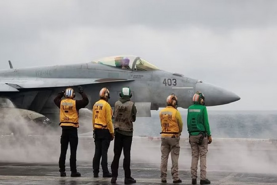 Crew members signal to a F/A-18E Super Hornet fighter jet preparing to take off for a routine flight on board the US USS Nimitz aircraft carrier during a routine deployment to the South China Sea, Mid-Sea, Jan 27, 2023. REUTERS