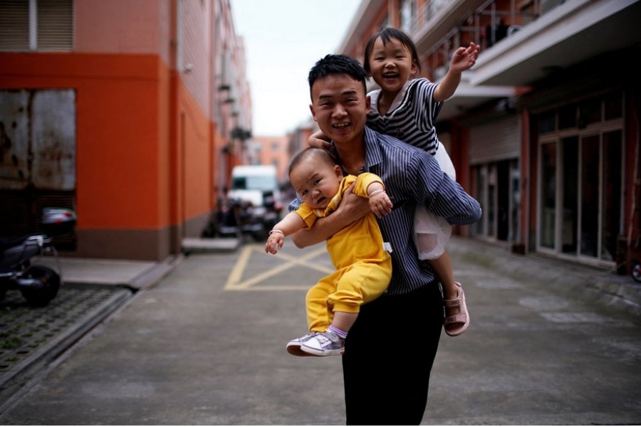 A father plays with his two children on the outskirts of Shanghai, China June 3, 2021. REUTERS/Aly Song/File Photo